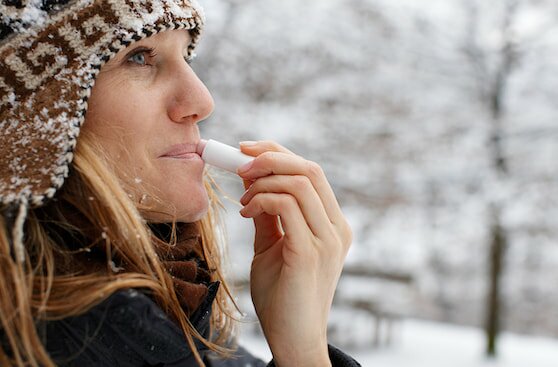 a woman applies chap stick in the snow